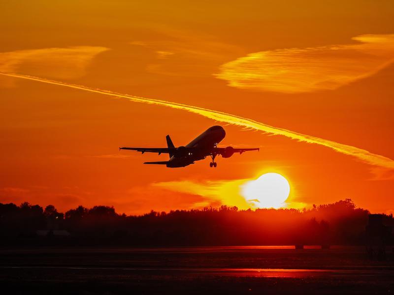 plane flying into sunset