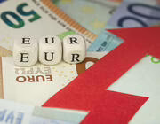 Dice reading "EUR" on pile of Euro banknotes